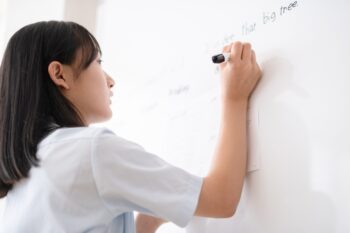 学生がホワイトボードに書く姿