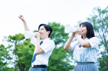 学生がメガフォンを持って応援するイメージ